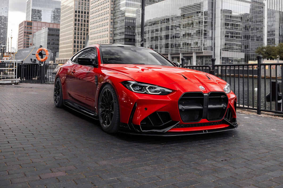 Red BMW G82 M4 with an ADRO V1 front bumper, black kidney grilles, front splitter and black wheels, parked by the water at Canary Wharf