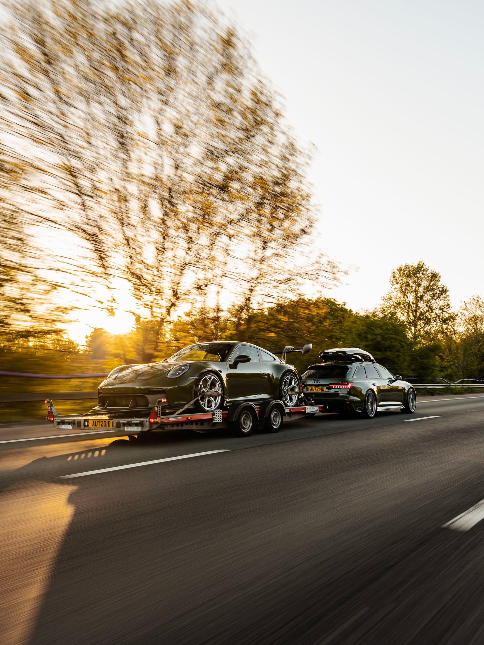 Rear of modified Porsche 992 GT3 with ADRO body kit on trailer with modified AUDI C8 RS6 towing 