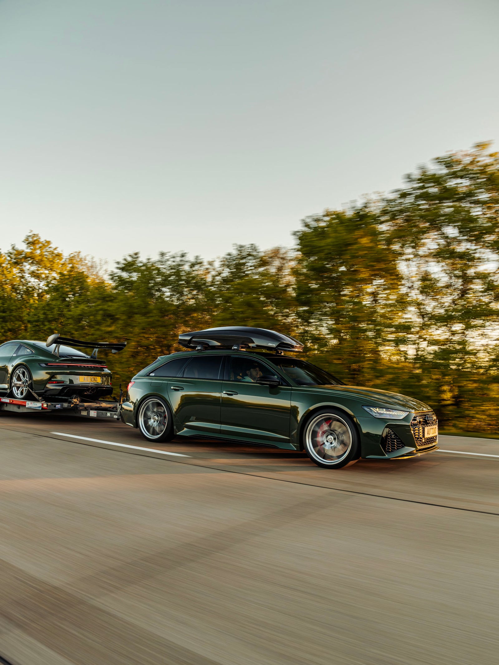 Front of modified AUDI C8 RS6 towing Porsche 992 GT3 with ADRO body kit on highway