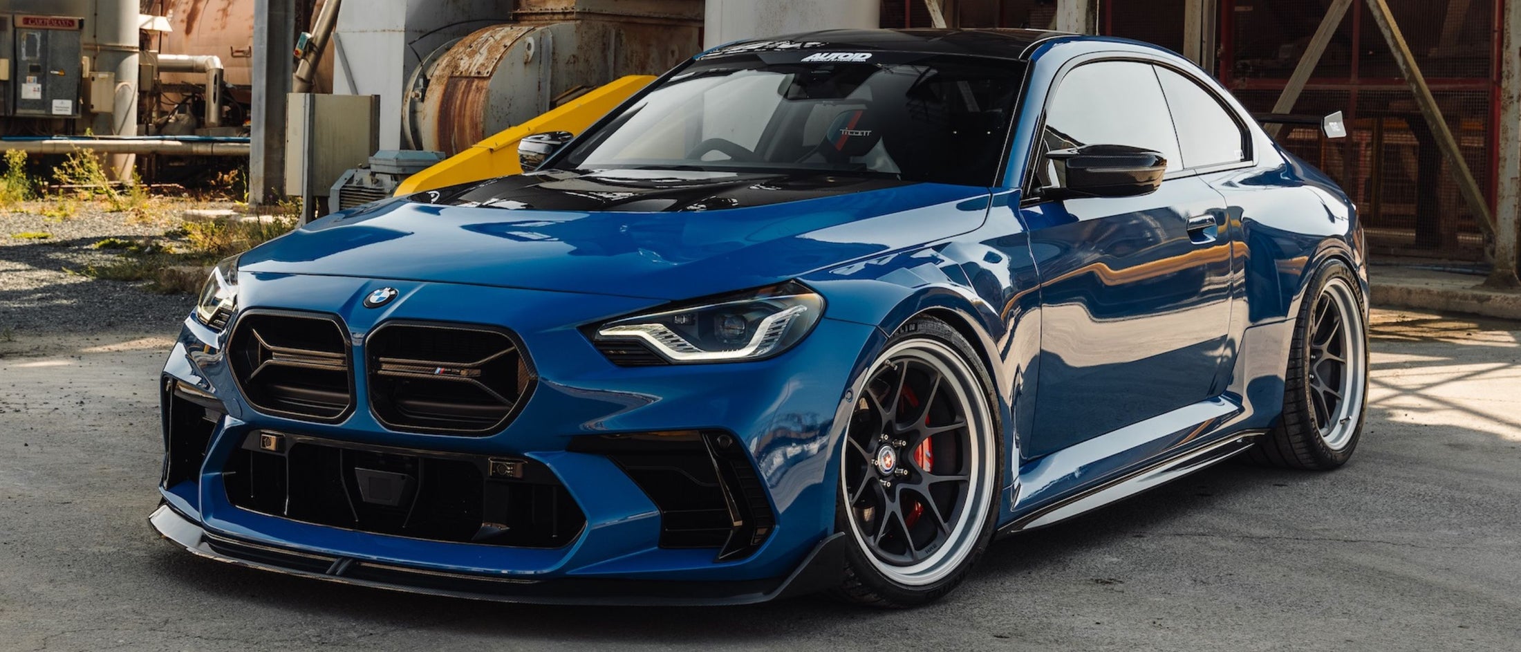 Blue BMW G87 M2 car parked in an industrial area