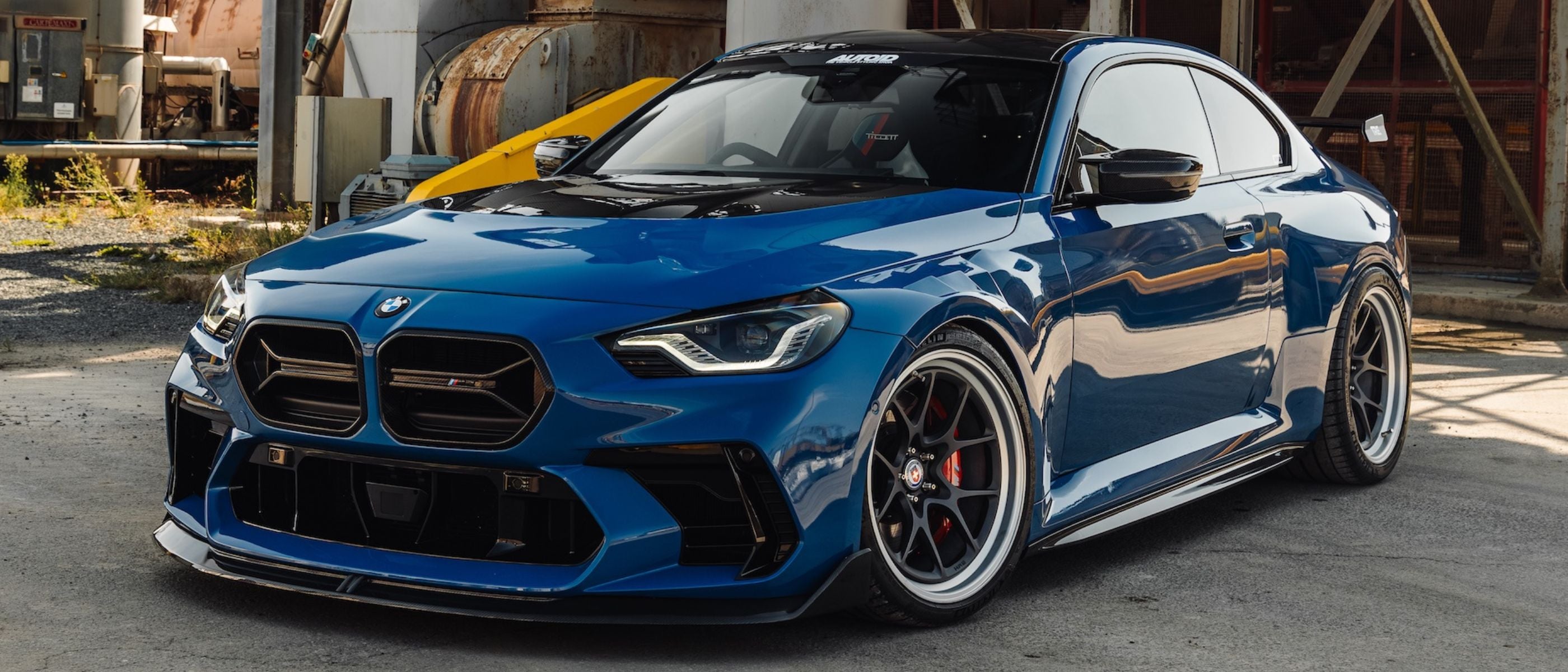 Blue BMW G87 M2 car parked in an industrial area